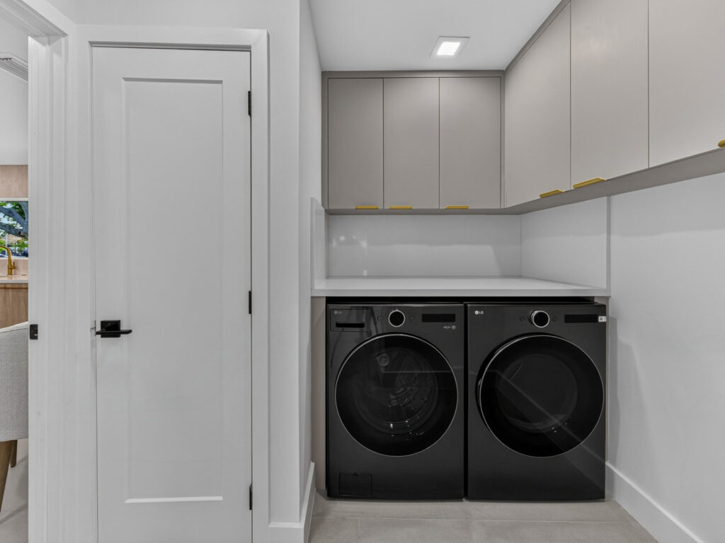 Interior laundry room with full-size washer and dryer and upper cabinets